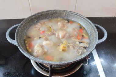 Boiled chicken in a pot broth of boiling water