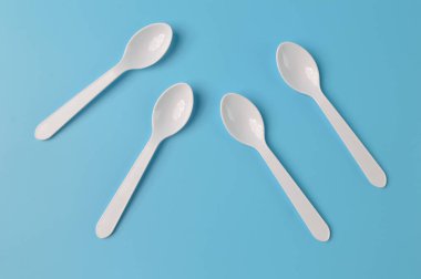 Mavi arka planda izole edilmiş plastik kaşıklar
