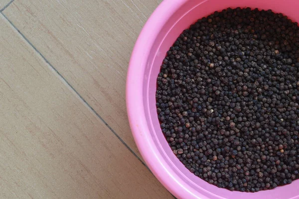 Black peppers or black peppercorns in a pink bowl