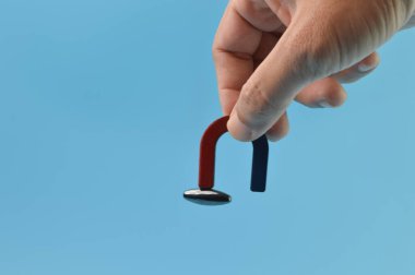 Man hand holding a magnet isolated on a blue background
