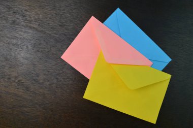 Top view of yellow, orange and blue envelopes on the table.