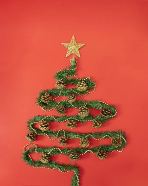 Üzerinde altın yıldız olan noel ağacıyla süslenmiş yaratıcı bir konsept. Yeni yıl düz uzandı pastel kırmızı arkaplan üzerine.