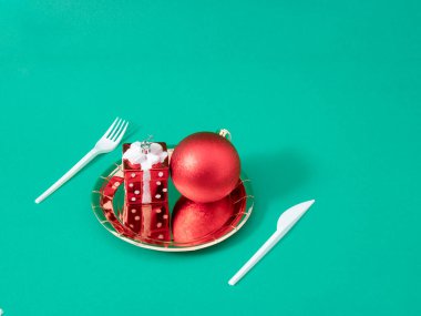 Yılbaşı yemeği kavramı kırmızı hediye ve altın tepside balo süslemesidir. Yaratıcı Kış Yeşil Arkaplanı.