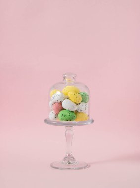 Yaratıcı Paskalya yumurtaları cam kaseye boyanmış. Pastel pembe arka plan. Bahar dekorasyonu.