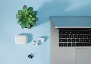 Yaratıcı ofis ortamı ve evde çalışmak için çalışma ortamı. Kahve, laptop, telefon ve kulaklıklar pastel mavi masa arkasında..