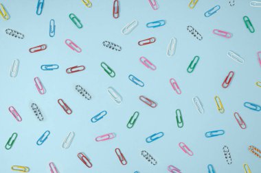 Creative office concept of multi-colored paper clips on pastel blue background