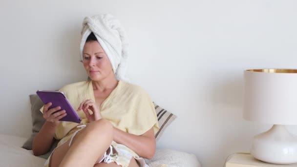 Bornoz Havlu Giymiş Bir Kadın Yatakta Oturuyor Dijital Tablet Kullanıyor — Stok video