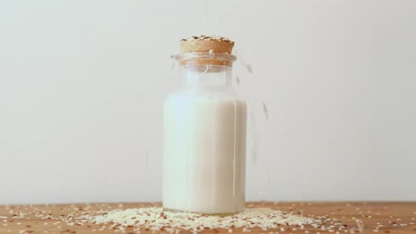 ゴマと亜麻の種子が種ミルクのボトルに振りかけられています 役に立つ飲み物 健康食品 人気と流行の食べ物 — ストック動画