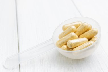 Plastik kaşıkta sarı bitkisel kapsüller, ilaç tedavisi, alternatif tıp, yakın çekim.