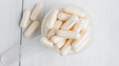 Plastik kaşıkta beyaz haplar veya kapsüller, ilaç tedavisi, alternatif tıp, yakın çekim, üst görünüm.