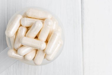 Plastik kaşıkta beyaz haplar veya kapsüller, ilaç tedavisi, alternatif tıp, yakın çekim, üst görünüm.