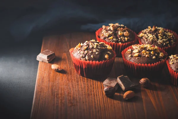 木の板にナッツを振りかけた自家製チョコレートマフィンやカップケーキ — ストック写真