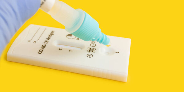 Process of testing with rapid antigen test kit for viral disease COVID-19 on yellow background.