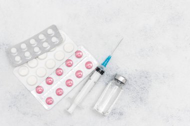 Beyaz arka planda tıbbi şırınga, ilaç hapları ve cam şişe, ilaç ve tedavi konsepti.