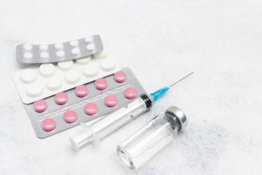 Beyaz arka planda tıbbi şırınga, ilaç hapları ve cam şişe, ilaç ve tedavi konsepti.