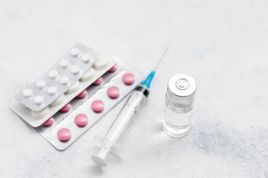 Beyaz arka planda tıbbi şırınga, ilaç hapları ve cam şişe, ilaç ve tedavi konsepti.