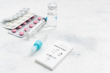 Viral hastalıklar için hızlı antijen test kiti COVID-19, ilaç tedavisi, haplar ve beyaz arka planda cam şişe.