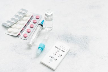 Viral hastalıklar için hızlı antijen test kiti COVID-19 pozitif sonuç, ilaç tedavisi, haplar ve beyaz arka planda cam şişe.