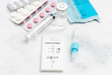 Viral hastalıklar için hızlı antijen test kiti COVID-19 pozitif sonuç, ilaç tedavisi, haplar ve beyaz arka planda cam şişe.