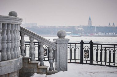 Amur Nehri 'nin karla kaplı şehir setinde bir balustrad. Kar yağıyor. Rusya Federasyonu 'nun devlet amblemiyle eskrim. Heihe City, Çin arka planda bulanık.