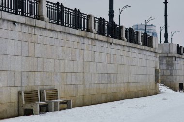 Kışın kar yağarken granit nehir seti. Kar taneleri düşüyor. Demir bir çit ve duvarda iki sıra var. Blagoveshchensk, Rusya.