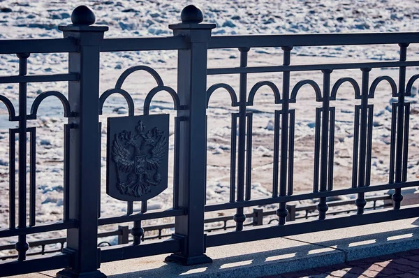 러시아 연방의 국가 상징물이 새겨진 도시 의검은 철조망. — 스톡 사진
