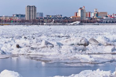 Bahar buzunun başlangıcı. Blagoveshchensk, Rusya 'dan Çin' in Heihe şehrinin manzarası. Amur Nehri 'nin bulanık buzu ve ön planda çözülmüş yamalar. Güneşli bir gün.