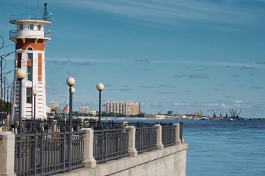 Güneşli bir yaz gününde Amur Nehri 'nin setindeki deniz feneri. Çit ve ışıklar. Rotunda ve liman turnaları. Blagoveshchensk, Rusya.