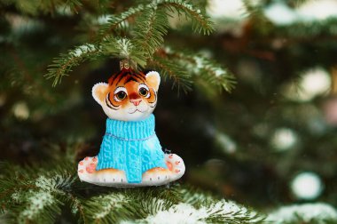 Kızıl Dicle karlı bir yılbaşı ağacının dalında. 2022 yılının kaplan sembolü. Noel ağacının üzerinde, ormanda Noel ağacı oyuncağı. Mutlu yıllar..