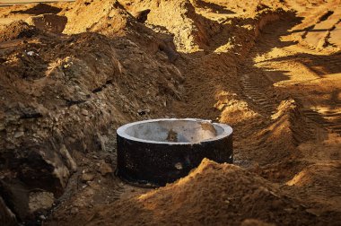 Şehir caddesindeki yeraltı tesislerinin yeniden inşası için bir site. Kum ve beton halka.