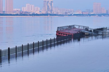Floating pontoon pier on the embankment of the city of Blagoveshchensk. Flooding on the Amur. Increased water level. Summer early foggy morning 2021.