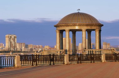 Autumn dawn on the embankment of the Amur River with a rotunda and balustrade. The reflection of the sun in the marble columns of the gazebo with a transparent dome. Blagoveshchensk, Russia.
