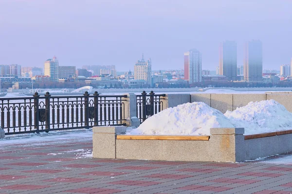 冬には花壇のあるベンチは 雪のドリフトで満たされています 街の堤防のプロムナード 二重使用の概念 背景には中国の平安市があります ロシアのBlagoveshchensk — ストック写真