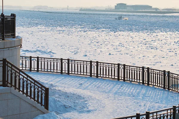 冬の朝に市の花崗岩の堤防 低レベルに降下します 背景に国境線を持つ中国の海岸 国境の川アムールは氷の洪水の破片で満ちている — ストック写真