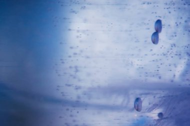 Aşağıdan yükselen hava kabarcıkları şeffaf mavi buzun içinde dondu. Buz deseni ve doku. Optik bozulma ve ışık kırılması. Odaklanmamış arka plan. Boşluğu kopyala.