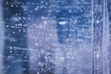 Aşağıdan yükselen hava kabarcıkları şeffaf mavi buzun içinde dondu. Buz deseni ve doku. Optik bozulma ve ışığın kırılması.