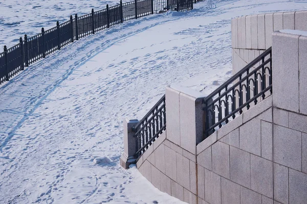 アムール川の雪に覆われた都市堤防の断片 冬の朝 金属と花崗岩 フェンスのある階段 白い雪のカーペットの上の人々や動物の痕跡 — ストック写真