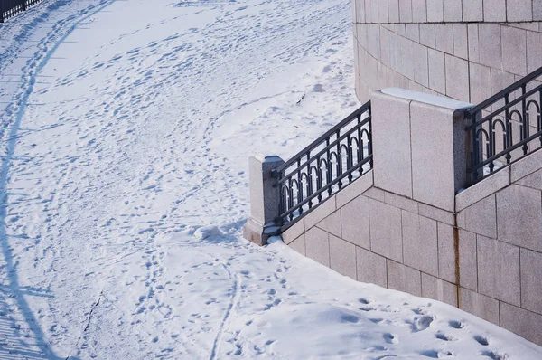 アムール川の雪に覆われた都市堤防の断片 冬の朝 金属と花崗岩 フェンスのある階段 白い雪のカーペットの上の人々や動物の痕跡 — ストック写真