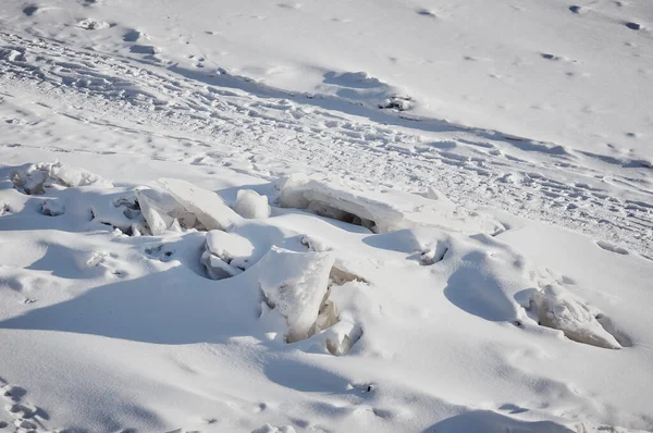 晴れた日には冬の風景。氷の流れのヒープと川の氷の雪に覆われた表面。道と道。雪の中の人や動物の痕跡。上からの眺め. — ストック写真