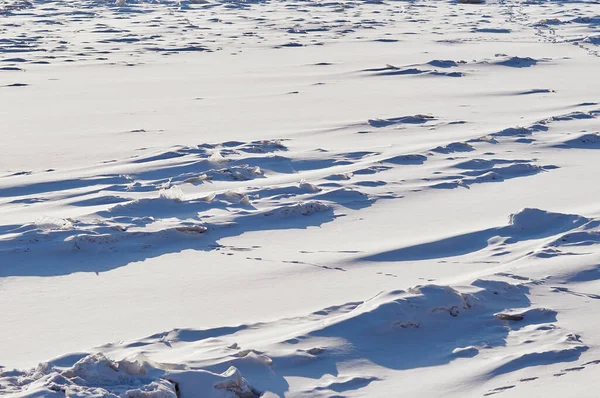 冬天的冰雪。天然质感在一个阳光明媚的日子里,河流上的光影.蜿蜒的狗迹。雪中的人和动物的踪迹. — 图库照片