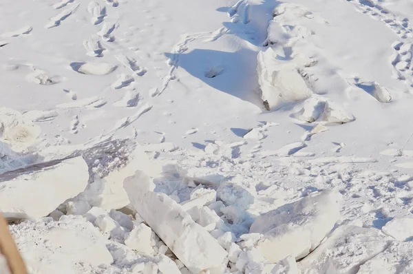 Neve e ghiaccio in inverno. Texture naturale. Luce e ombre in una giornata di sole sul fiume. Tracce di cani avvolgenti. Tracce di persone e animali nella neve. — Foto Stock