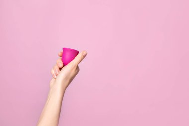 Genç bir kadın elinde pembe bir adet bardağını katlıyor. Pembe arka plan. Mesaj için yer var. Çevre dostu silikon. Kadın sağlığı döngüsü Yüksek kaliteli fotoğraf
