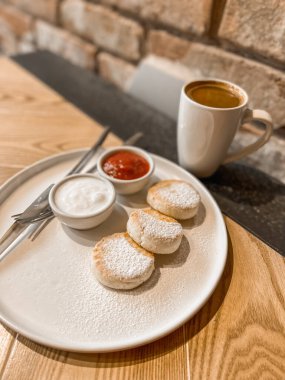 Ekşi krem peynirli kek, reçel ve masaya bir fincan kahve.