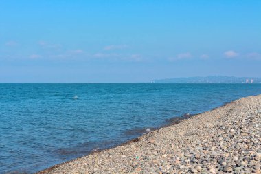 Güneşli bir günde kristal berrak bir su ve kayalık plajlı bir arka plan 