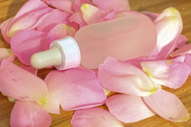 Doğal pembe taçyapraklı arka planda, üzerinde temiz bir şişe var.