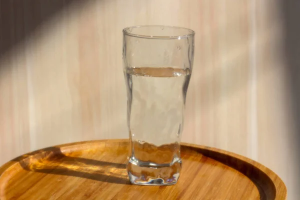 Un vaso de agua de pie sobre la pequeña mesa — Foto de Stock