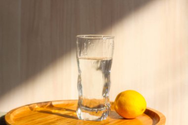 Sabah ışığında bir bardak su ve limon.
