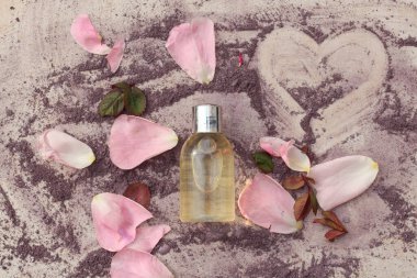 Taze gül yaprakları ve mor toz boyayla çevrili bir güzellik ürünü şişesinin düz bir bileşimi.