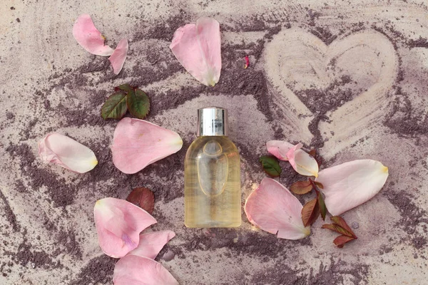 Taze gül yaprakları ve mor toz boyayla çevrili bir güzellik ürünü şişesinin düz bir bileşimi.