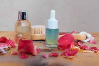 Kozmetik şişeleri ve ahşap kozmetik fırçası taze gül yapraklarıyla masada duruyordu.